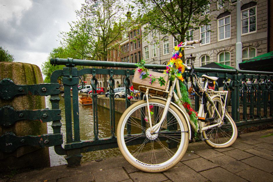 A flower-adorned bicycle on a bridge over an Amsterdam canal